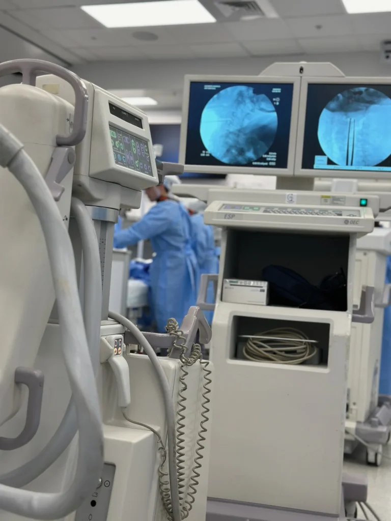 Active GE OEC C-Arm workstation displaying clear spinal fluoroscopy imaging during a live procedure in a Sarasota surgery center.