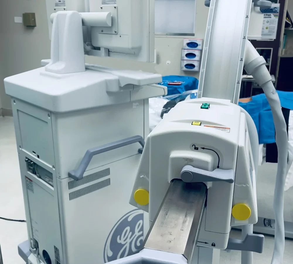 GE OEC 9900 Elite C-Arm positioned beside an operating table in a Florida operating room, prepared for fluoroscopic imaging prior to a surgical procedure.